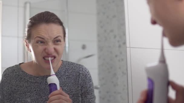 女性は鏡に映るバスルームで朝の灌漑で歯をきれいにする — ストック動画