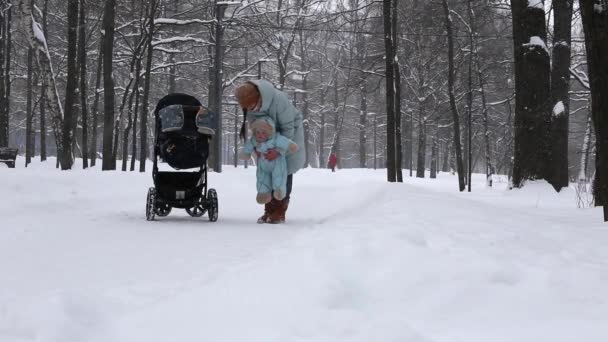 Matka chodí s malým dítětem v lese v zimě ve sněhu — Stock video