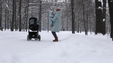 Bir anne Rusya 'da karla kaplı bir parkta yürürken küçük bir çocuğu fırlatır.