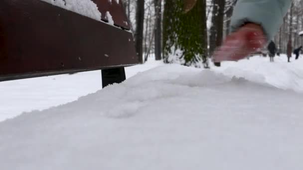 Az emberek kézzel takarítják el a havat a padról télen az utcán. — Stock videók