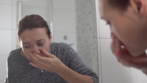 Жінка з закладеним носом миє обличчя вранці у ванній — стокове відео