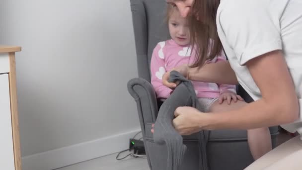Pečující matka si doma obléká punčocháče na svou dcerku — Stock video