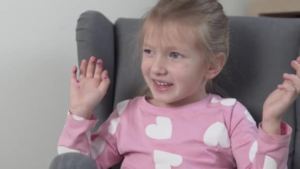 Un primer plano de una linda niña en casa en una silla — Vídeos de Stock