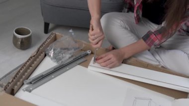Bir kadın bir sürgüyü masadan ayrıntıya çevirir.,