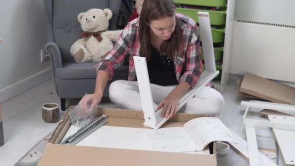 Kobieta zbiera biurko zgodnie z instrukcjami domu. — Wideo stockowe