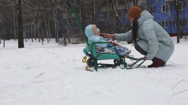 Matka jeździ na swoim synu na sankach w śniegu zimą. — Wideo stockowe