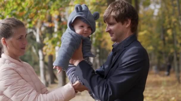 Žena míjí roztomilé dítě na paži muže na rodinné procházce — Stock video