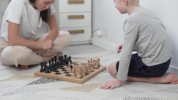 Mutter und Sohn spielen zu Hause auf dem Fußboden Schach — Stockvideo