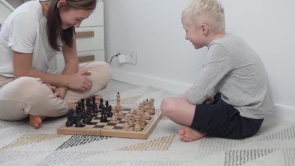 Мама учит сына играть в шахматы дома — стоковое видео
