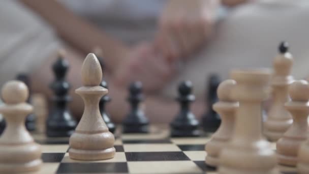 Primer plano del ajedrez en un tablero de ajedrez, piezas blancas en foco — Vídeos de Stock
