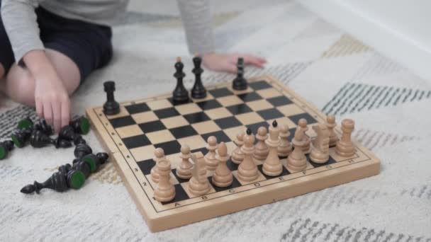 O menino coloca peças de xadrez preto em um tabuleiro de xadrez antes do jogo — Vídeo de Stock