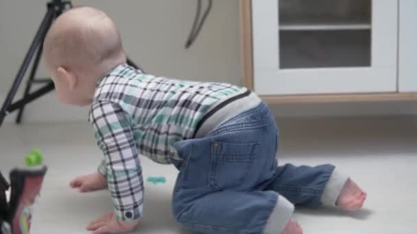 Un niño pequeño se arrastra por la habitación de los niños con juguetes — Vídeo de stock