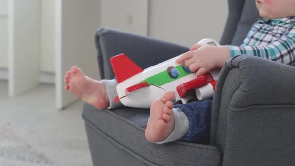 Маленький ребенок играет с самолетом в детском кресле дома — стоковое видео