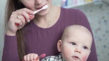 Genç bir anne, dişlerini evde küçük bir diş fırçasıyla fırçalamayı öğretir.