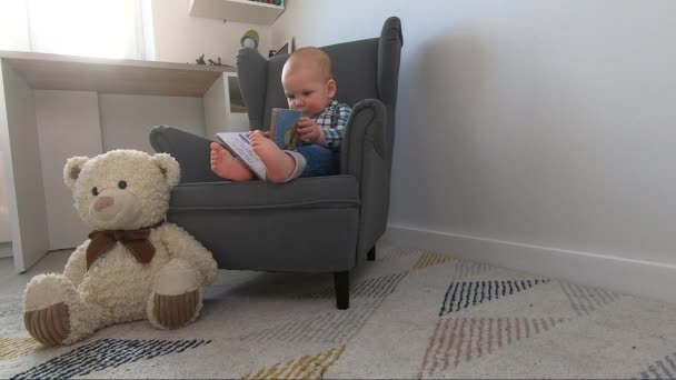 Маленький бизнесмен в футболке и джинсах сидит в мягком кресле — стоковое видео