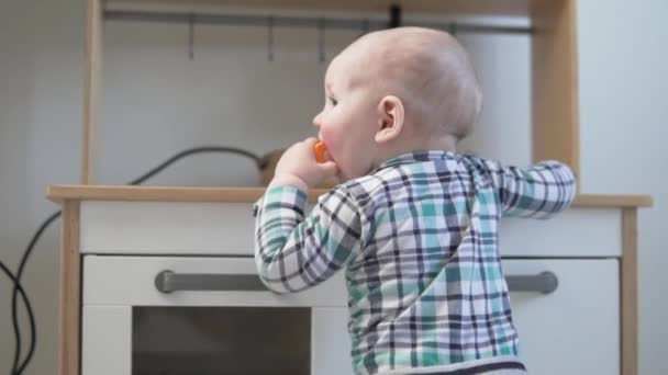 Um miúdo lambe um brinquedo de plástico em casa — Vídeo de Stock