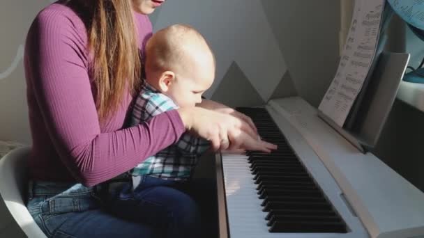 Una madre con un bebé toca el piano en casa — Vídeo de stock