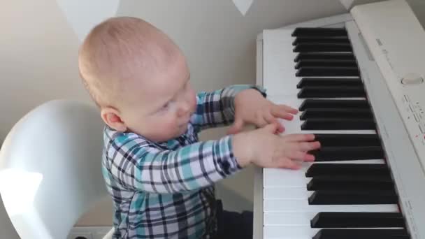 Een klein kind klopt met zijn handen op de toetsen van een elektronische piano — Stockvideo