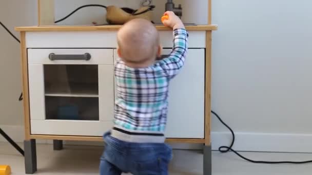 Un petit garçon se tient debout avec le soutien à la cuisine pour enfants à la maison — Video