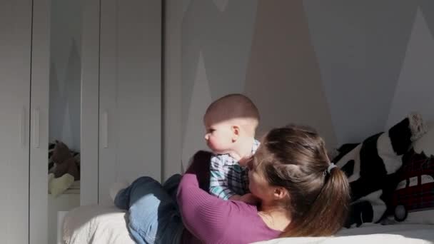 若い母親が幼い息子とベッドで遊び — ストック動画