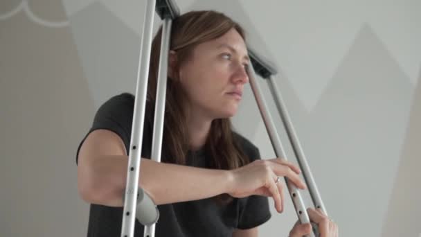 Eine traurige Frau mit einem Stich in die Hände und einem bandagierten Bein sitzt auf dem Bett — Stockvideo