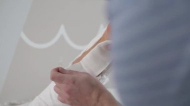 Doktor, aşil tendonunu diktikten sonra bacağına bandaj yapar..