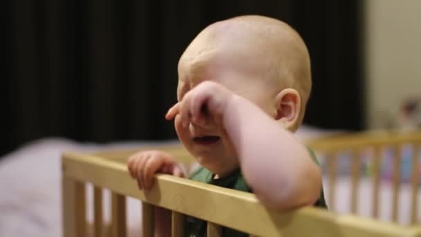 Uma criança pequena chora em um berço. — Vídeo de Stock