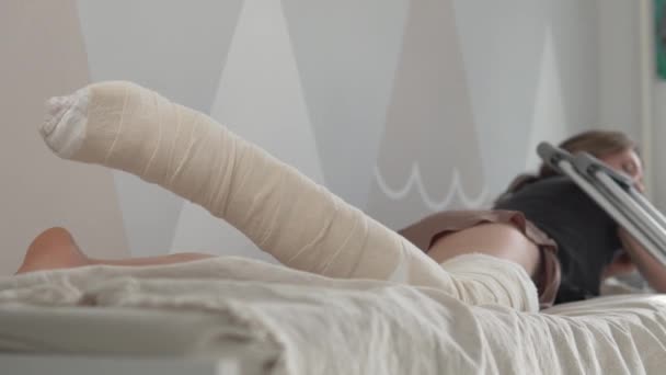 Μια γυναίκα με ένα πόδι σε γύψο ξαπλώνει στο κρεβάτι — Αρχείο Βίντεο