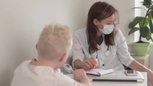 A beautiful female doctor measures the saturation of oxygen in a child — Stock Video
