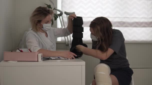 The doctor shows the patient in plaster orthosis and explains how to use it at the hospital — Stock Video