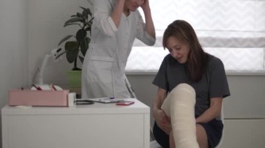 Hastanedeki bir kadın bacağındaki tendonu yırttıktan sonra bir doktor rehabilitasyon uzmanıyla görüşüyor.