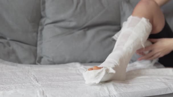 Kvinnors hand tar bort den medicinska bandage från gips languet. — Stockvideo