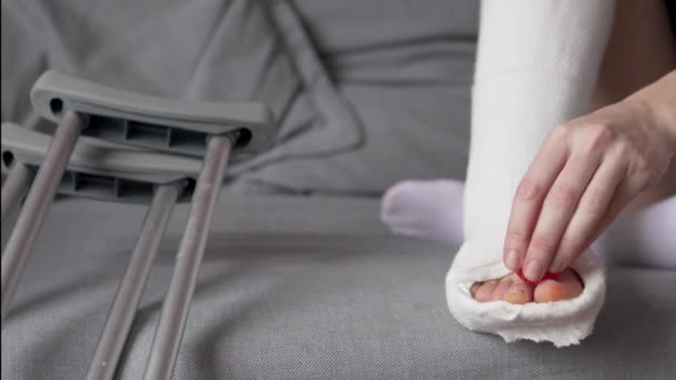 Egy bekötözött lábú nő masszírozza az ujjait egy masszázsgolyóval. — Stock videók