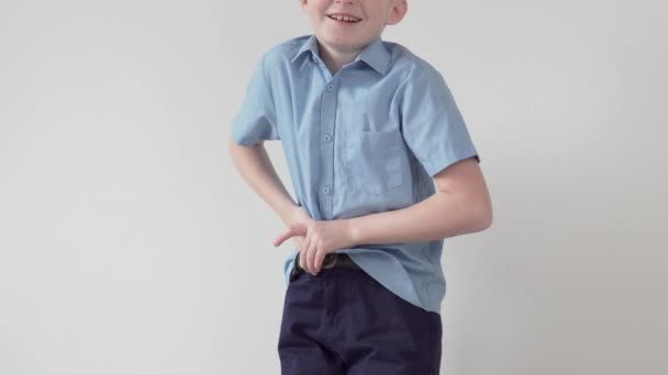 Ένα όμορφο ξανθό αγόρι βάζει το πουκάμισό του στο παντελόνι του. — Αρχείο Βίντεο