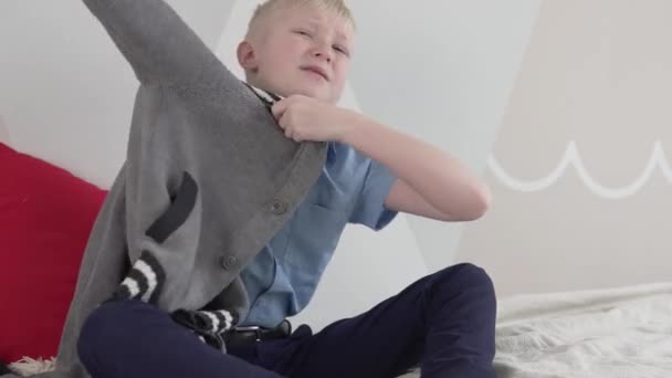 Un hermoso chico rubio lleva una chaqueta caliente en casa — Vídeo de stock
