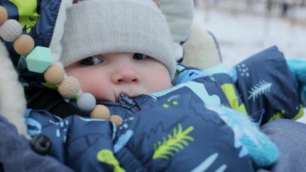 Close-up, a small child sits in a stroller in winter — Stock Video