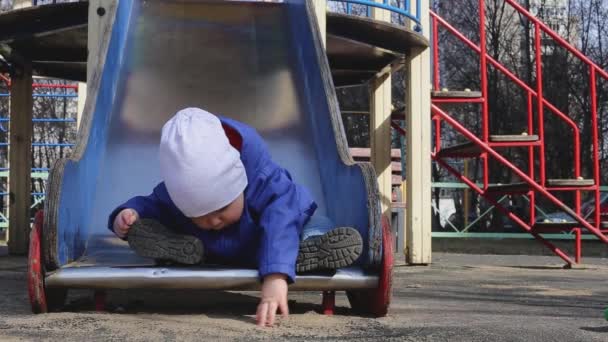 Um menino caminha no parque infantil na primavera — Vídeo de Stock
