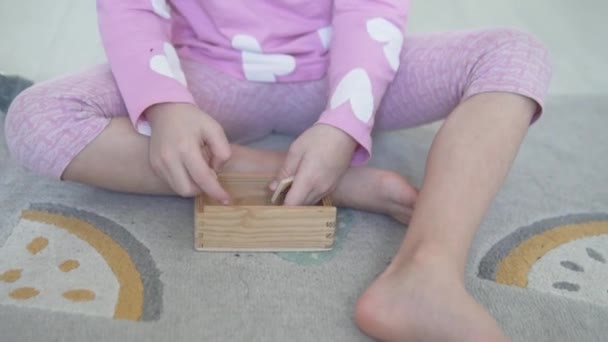小さな女の子は木の箱のドミノを削除します。 — ストック動画