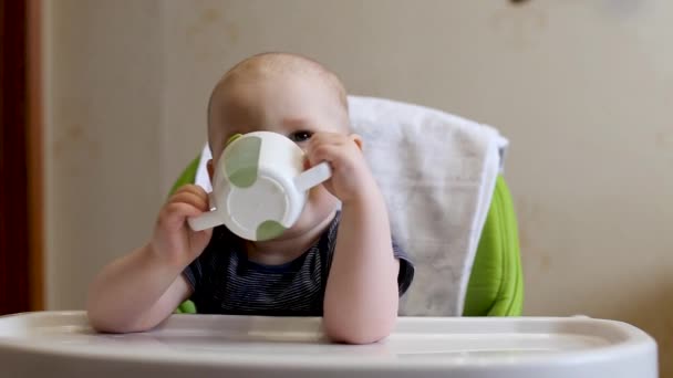 Un bambino beve acqua da un'acqua potabile a un tavolo per bambini — Video Stock