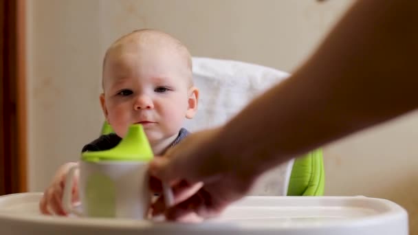 母親は小さな子供に水ボトルを与え、少年は家で熱心に水を飲む — ストック動画