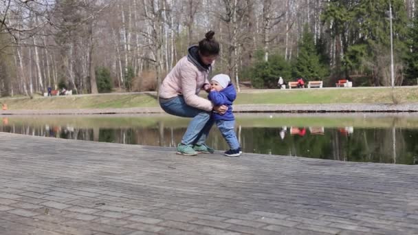 Uma jovem mãe caminha com uma criança pequena no parque para uma caneta — Vídeo de Stock