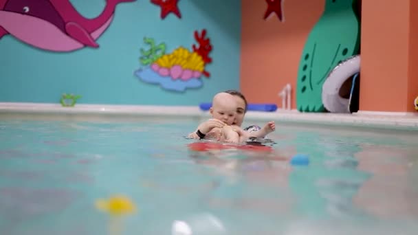 Pływanie z małym dzieckiem w basenie dla dzieci z trenerem — Wideo stockowe