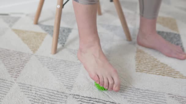 Una mujer rueda una bola de masaje verde con su pie — Vídeo de stock
