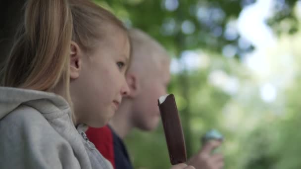 Gros plan, les enfants mangent de la glace dans le parc au printemps — Video