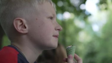  Sarışın bir çocuk baharda bir parkta dondurma yiyor..