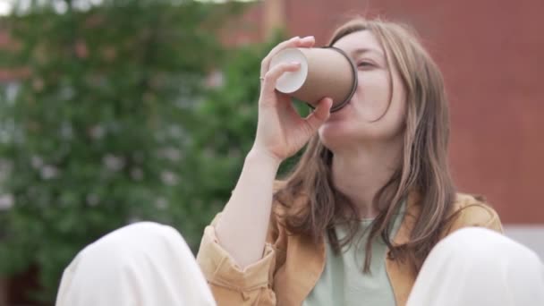 Крупним планом, модна жінка-туристка п'є каву в парку влітку — стокове відео