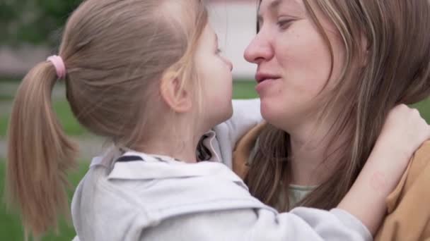 Mam en dochtertje knuffelen elkaar op een wandeling, close up. — Stockvideo