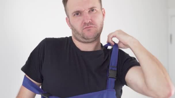 Nahaufnahme, ein gutaussehender männlicher Arbeiter zieht eine Arbeitsuniform an und zwinkert — Stockvideo