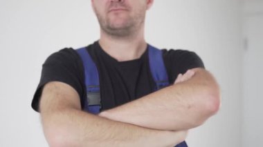 Elleri yakın plan, işçi üniformalı bir adam kollarını göğsünde kavuşturur ve ileri doğru gerer.