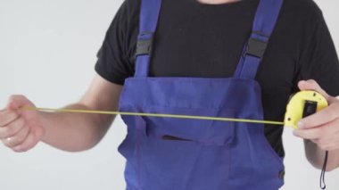 Yakın plan, erkek müteahhit bir santimetre kurdele tutuyor.
